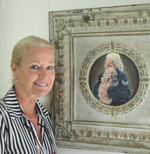 Patty stands by a painting of herself holding a puppy mill dog just pulled from a horrific living situation